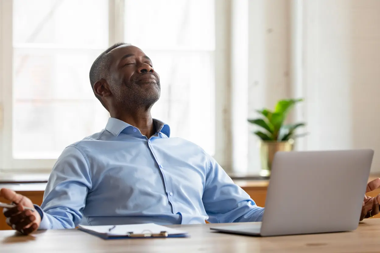 homme-detendu-bras-ouverts-devant-ordinateur-ambiance-bureau Homme détendu les bras ouverts devant un ordinateur, en ambiance bureau calme après burn-out, illustrant l’hypnose burn out récupérer énergie.